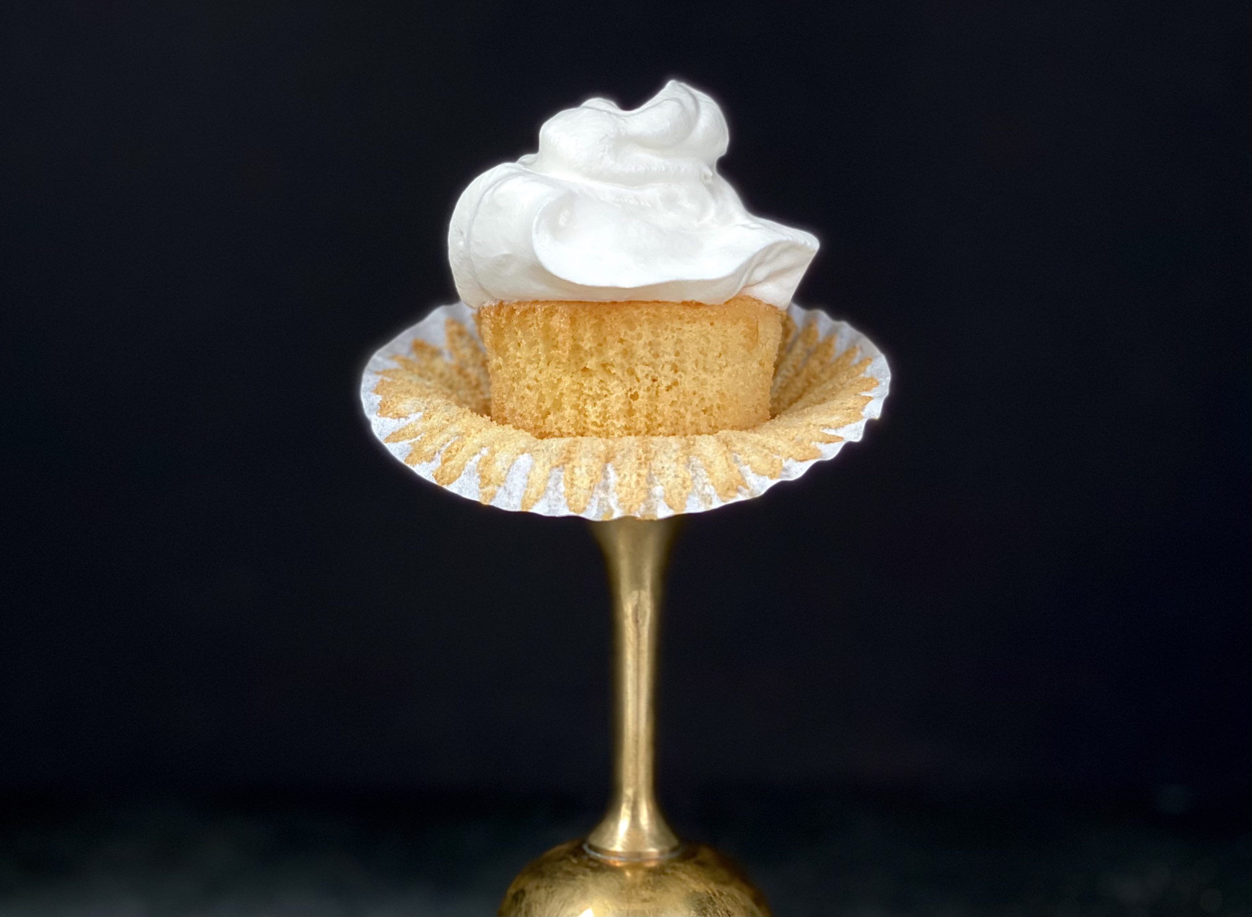 Close-up photograph of chiffon cupcakes, showcasing its light and fluffy texture with a delicate swirl of frosting on top. The cupcakes appear moist and airy, with a golden-brown exterior.