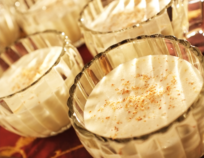 Aged eggnog in glass goblets topped with eggnog.
