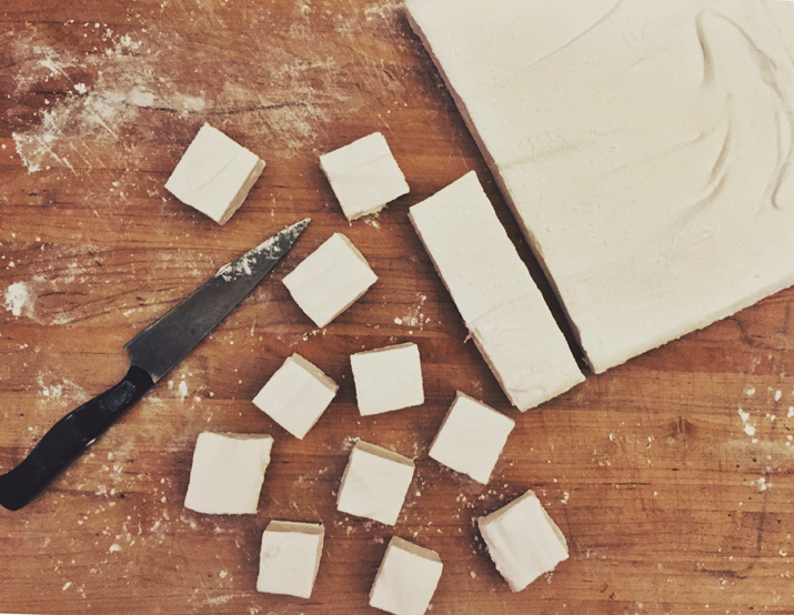Homemade vanilla marshmallows on a wooden cutting board.