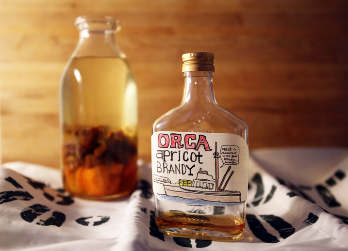 Homemade apricot brandy in a glass bottle with a handmade label that reads "Orca Apricot Brandy."