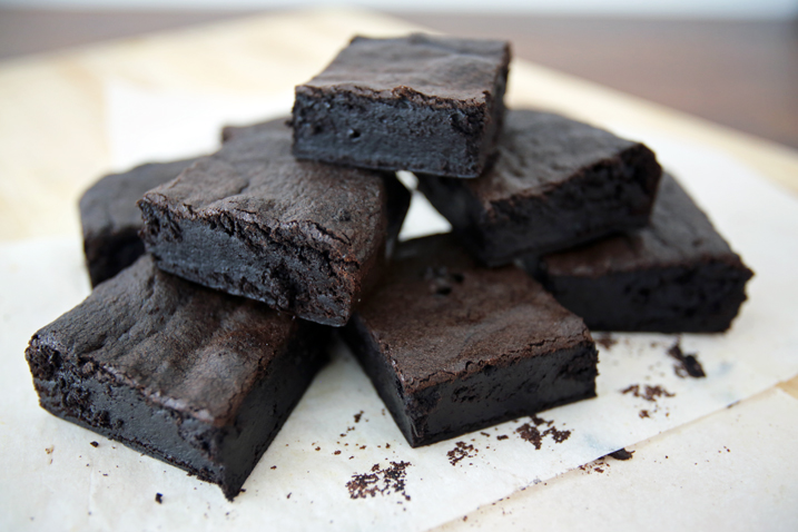 Coca brownies stacked on parchment paper.