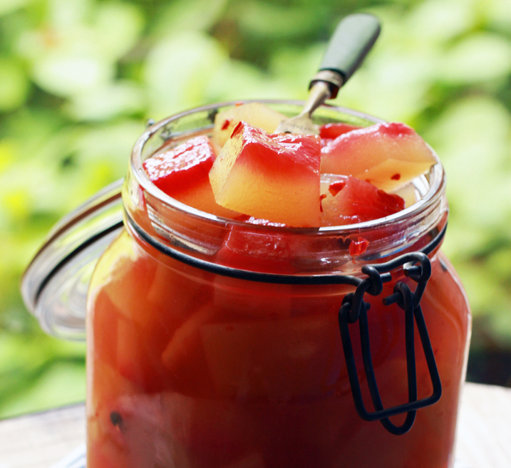 Watermelon rind pickles in a jar with pickling spices