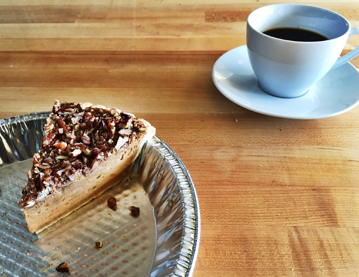 A slice of Alton Brown's silky sweet potato pie in a metal pie tin next to a white mug of coffee.