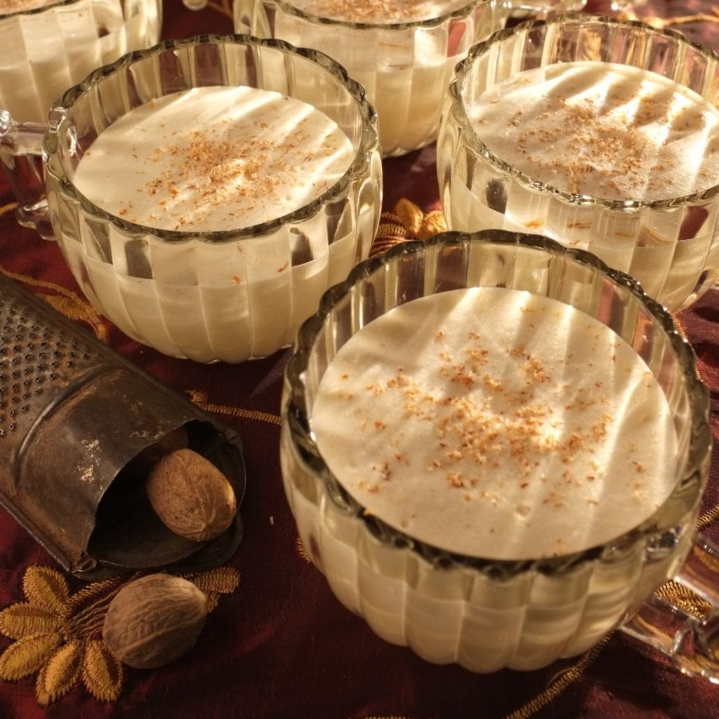 Classic eggnog in glass goblets topped with freshly grated nutmeg.