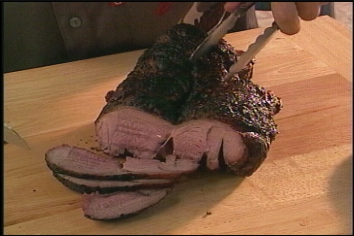 Silence of the leg of lamb sliced on a wooden cutting board on the set of Good Eats.