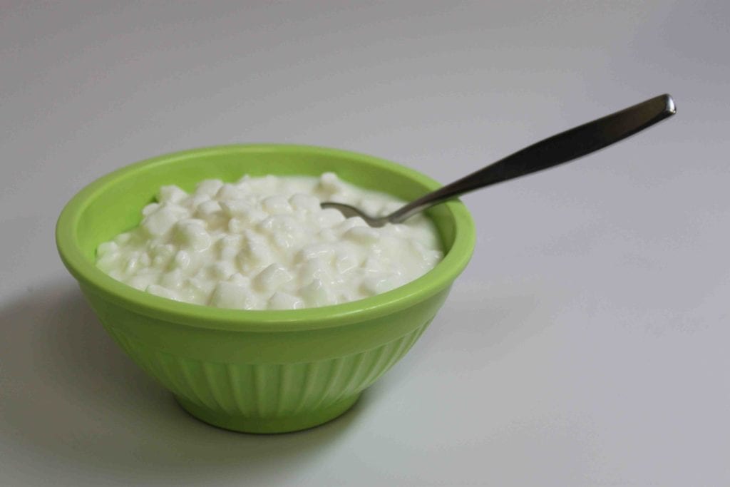 Quick cottage cheese in a green bowl with a spoon.