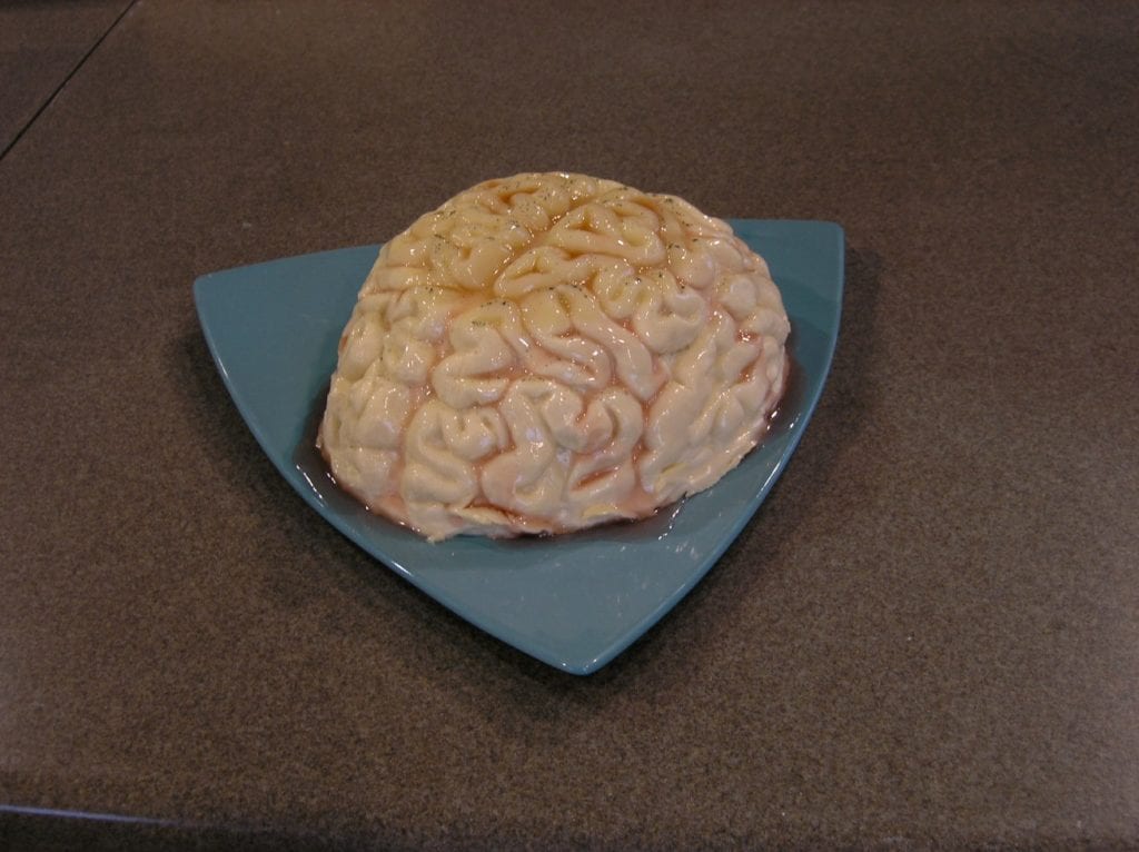 Panna cotta brain with cranberry glaze on a blue triangular plate.