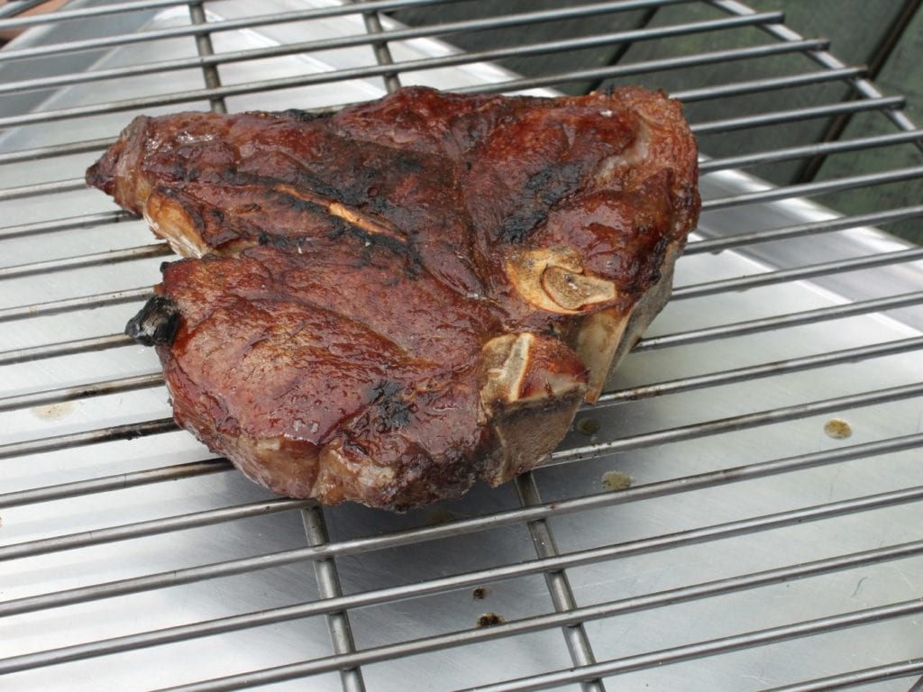 Dry-aged chimney porterhouse on a grill grate on the set of Good Eats.
