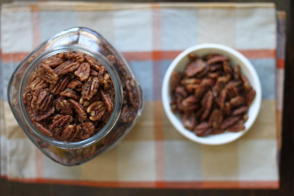 Alton Brown's spicy pecans in a glass jar and a white ramekin.