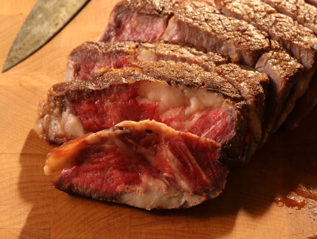 Reverse-sear ribeye steak sliced diagonally against the grain.