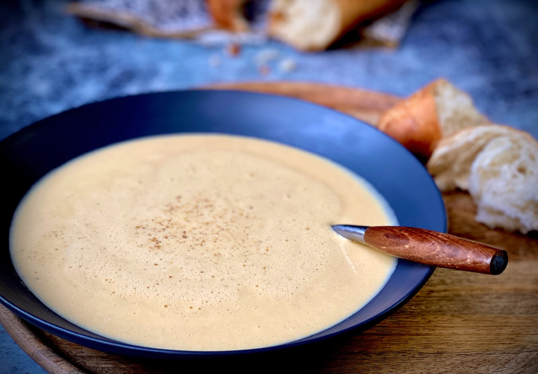 Creamy cheese soup in a bowl with hunks of bread on the side.