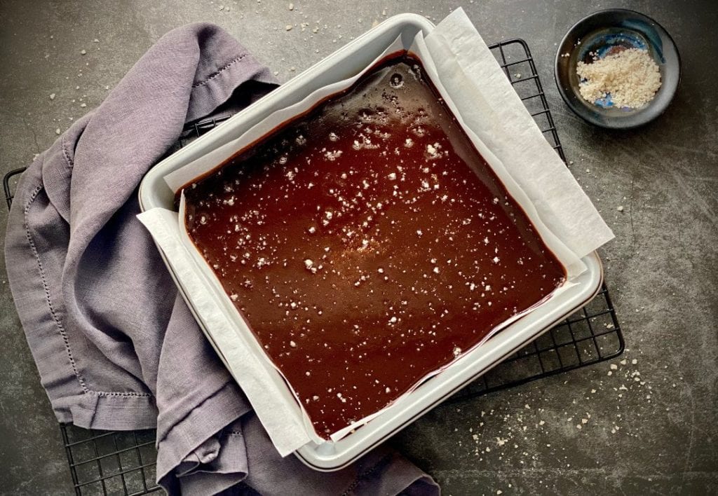 Homemade salted caramels cooling in a parchment paper-lined baking dish.