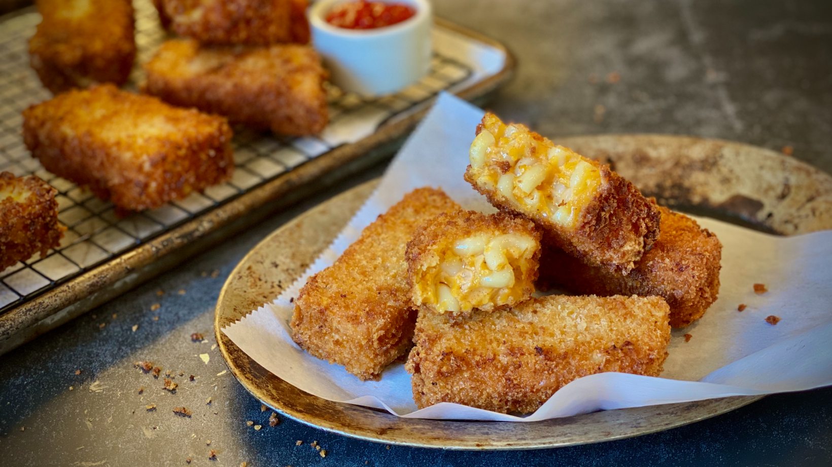 Fried mac and cheese sticks on a paper towel-lined plate.