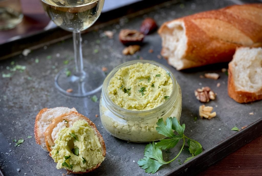 5-ingredient cheese spread with parsley in a glass jar served with a baguette and a glass of white wine.
