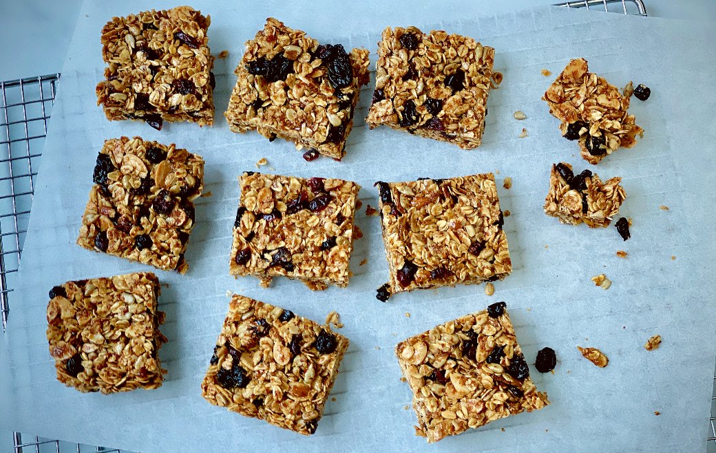 Homemade granola bars cut into squares on a piece of parchment paper.