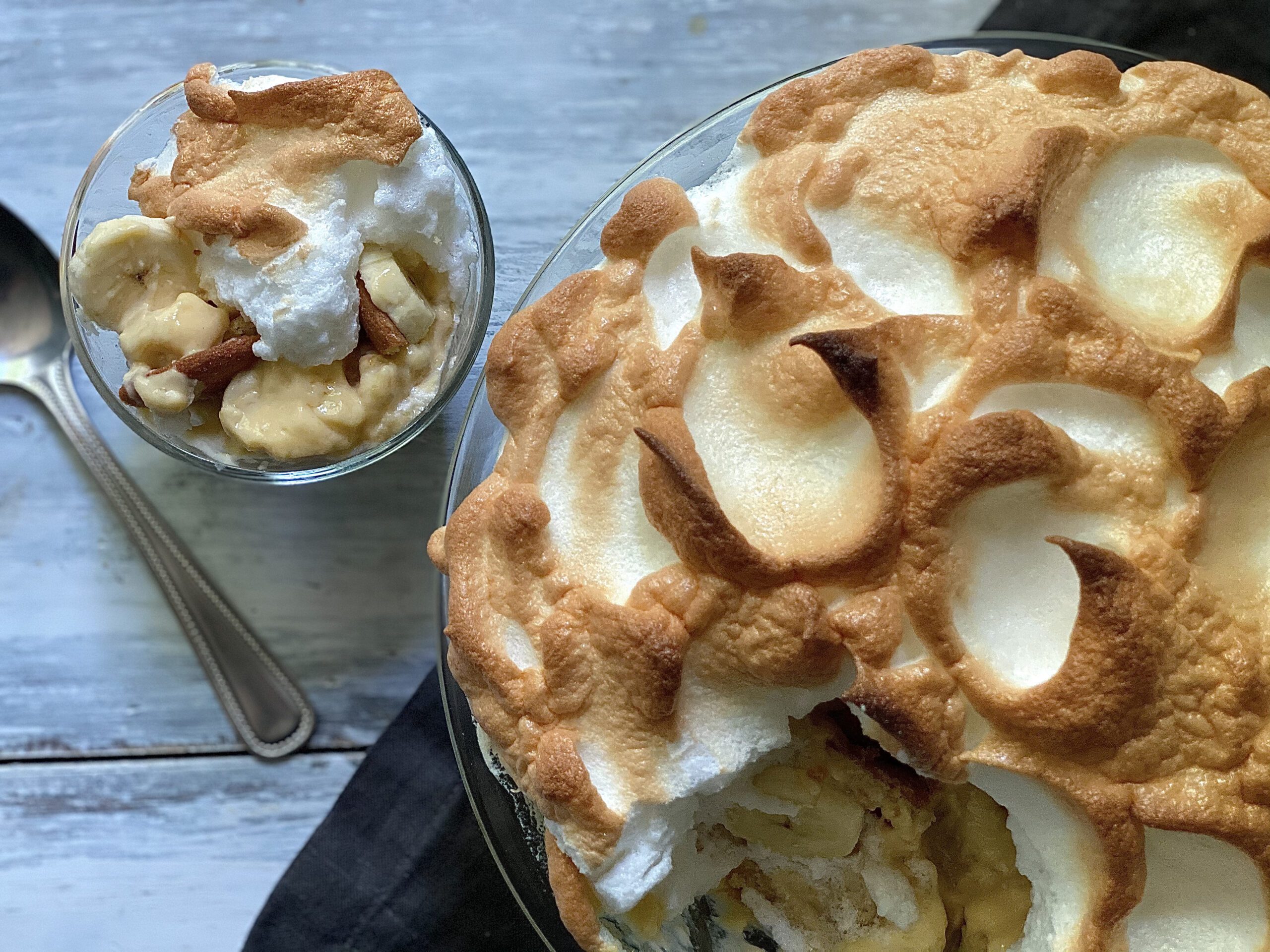 Golden brown baked banana pudding topped with fluffy meringue, a classic Southern dessert with homemade vanilla wafers.