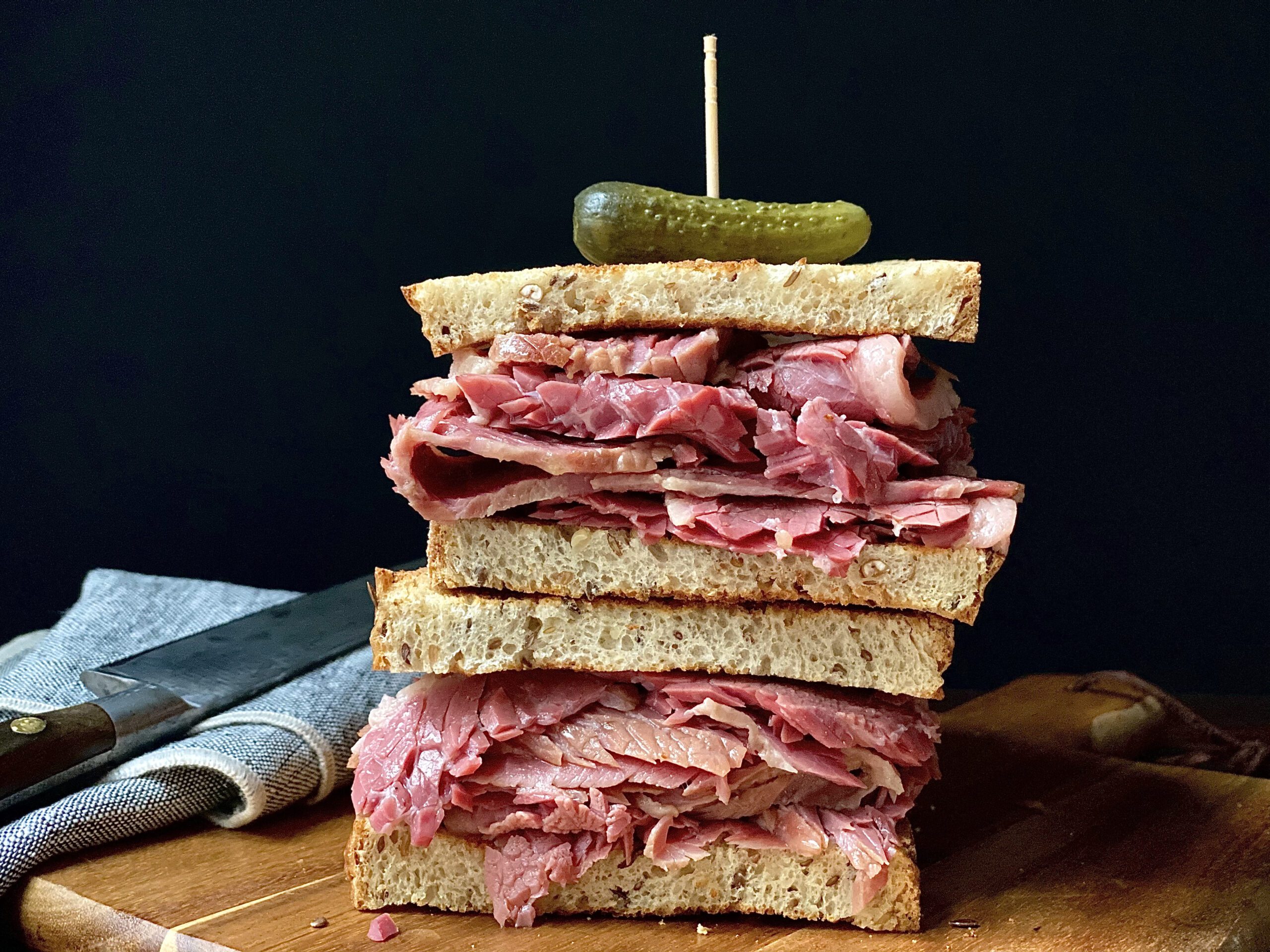 Tender and juicy, slow cooker corned beef served on toasted rye bread with a pickle on top