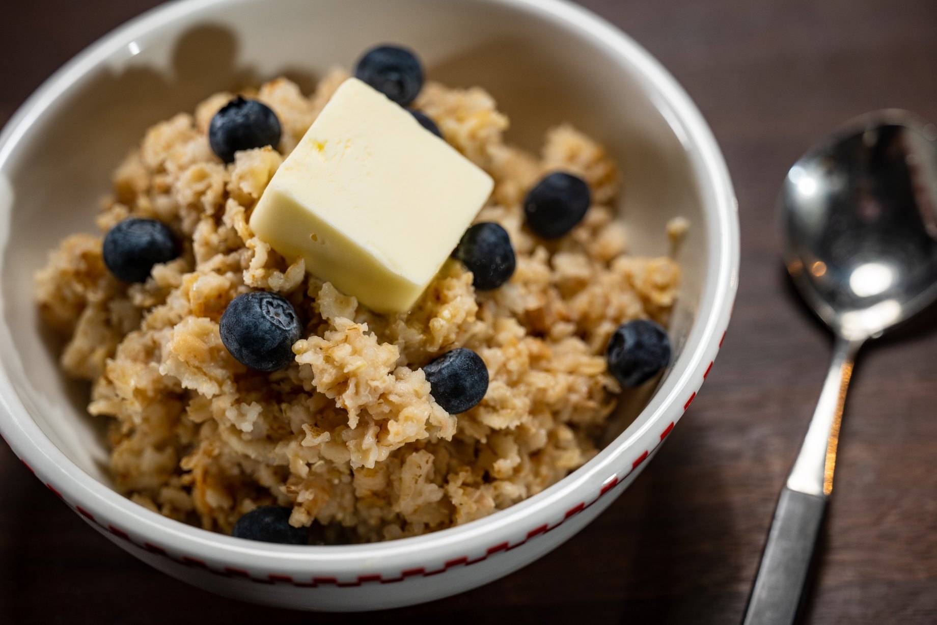 Jussst right oatmeal in a white bowl with blueberries and butter.
