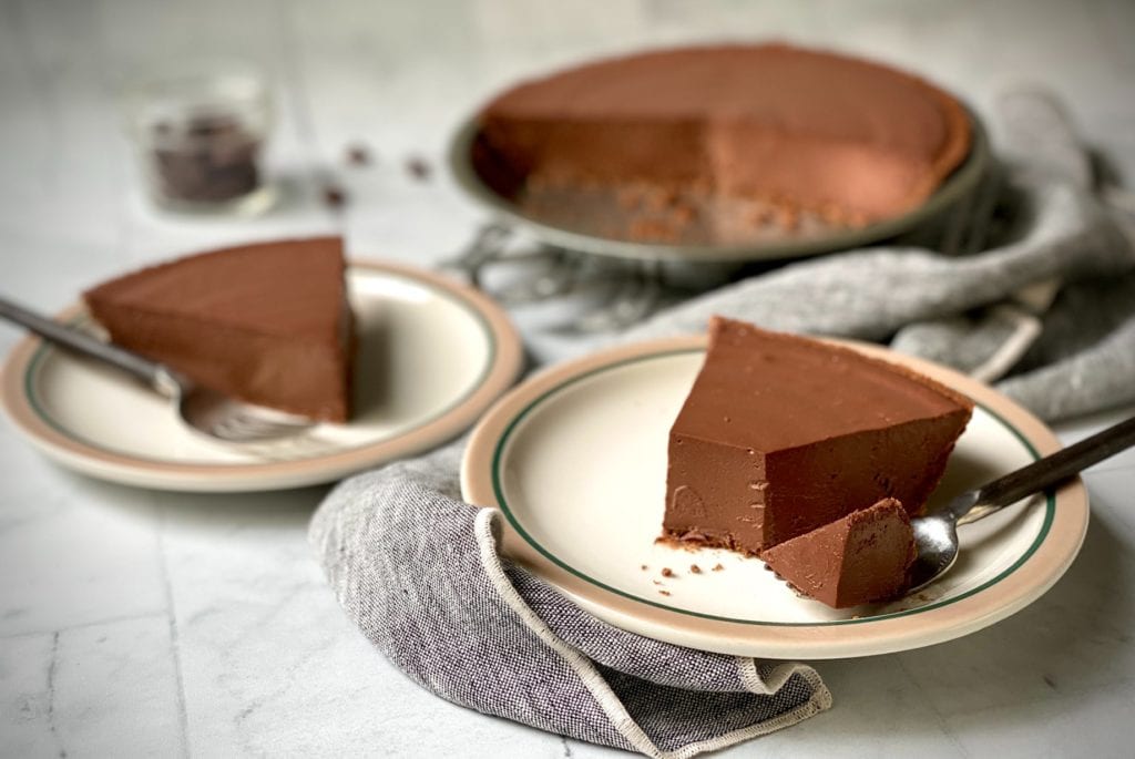 Dairy-free chocolate pie slice on a plate with a bite missing.