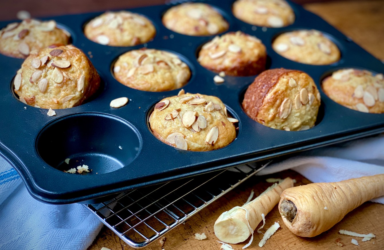 Parsnip muffins topped with sliced almonds cooling in a muffin tin.