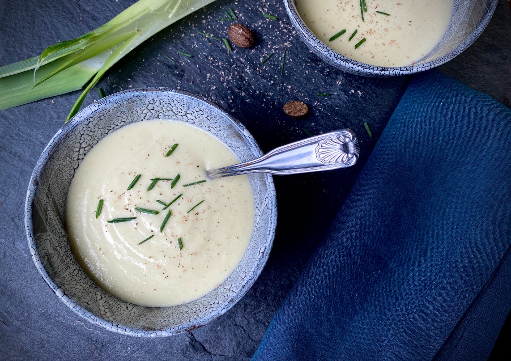Leek potato soup in a bowl topped with chives.