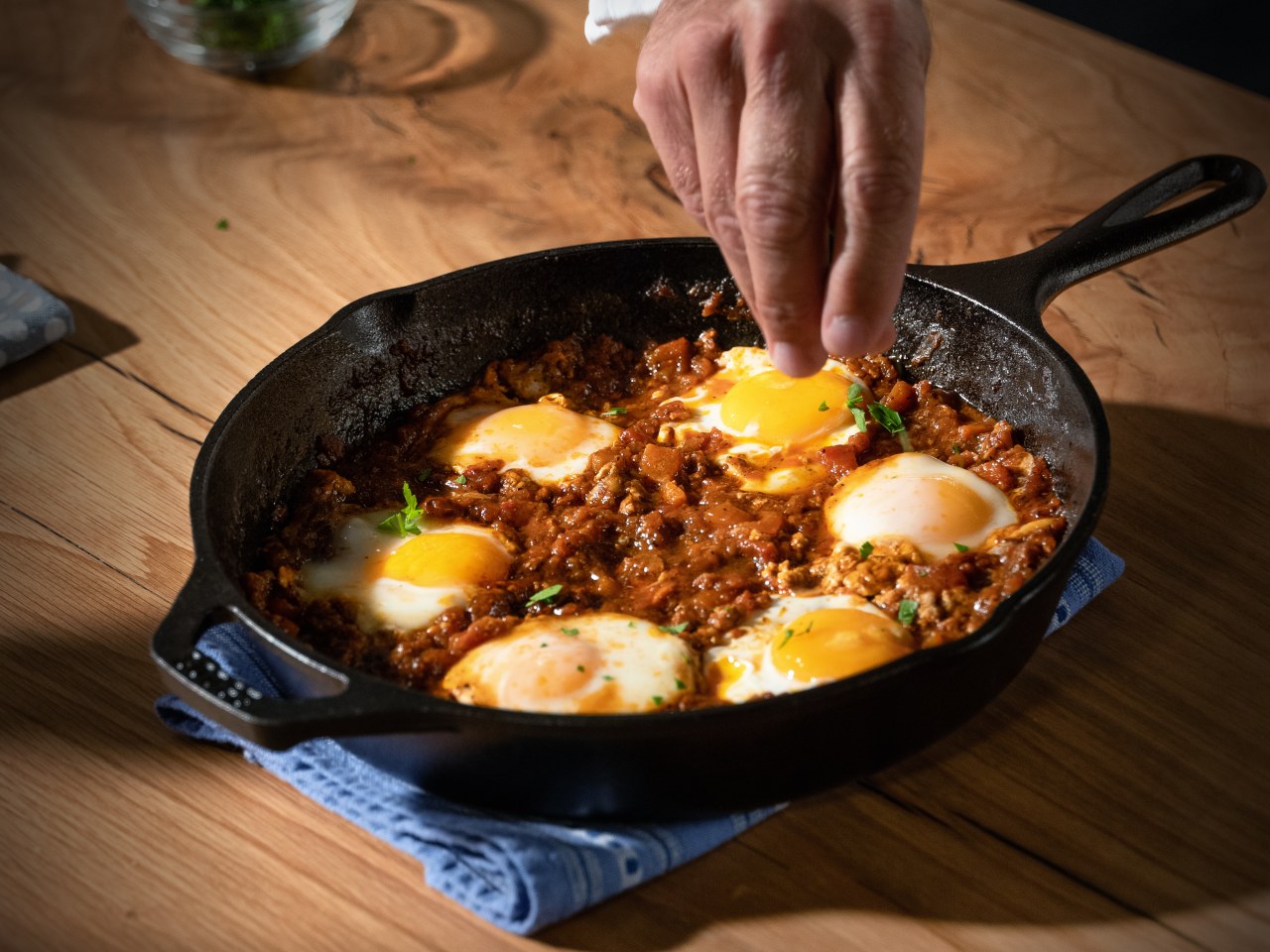Red Shakshuka with six poached eggs in a large cast-iron skillet.