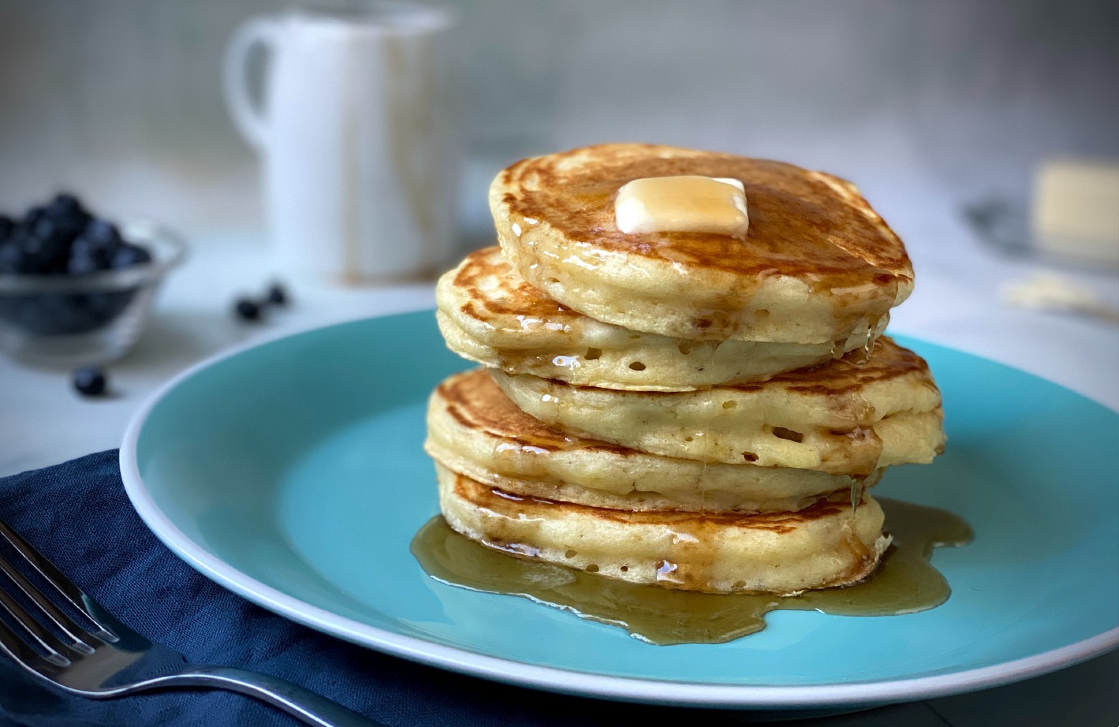Semi-instant pancakes stacked on a plate, drizzled with maple syrup, and topped with a pat of butter.