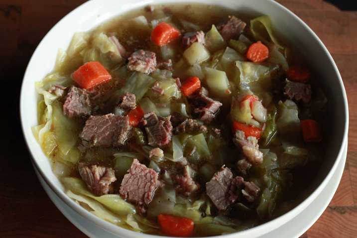 Corned beef and cabbage recipe in a white bowl.
