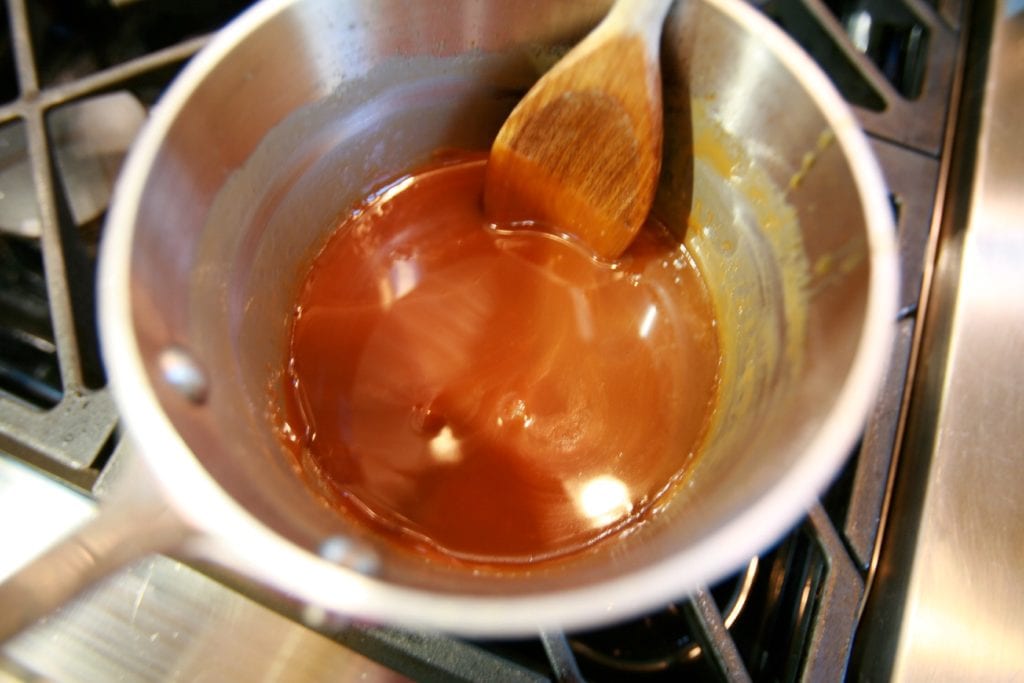 Homemade caramel sauce made by Alton Brown in a small saucepan.