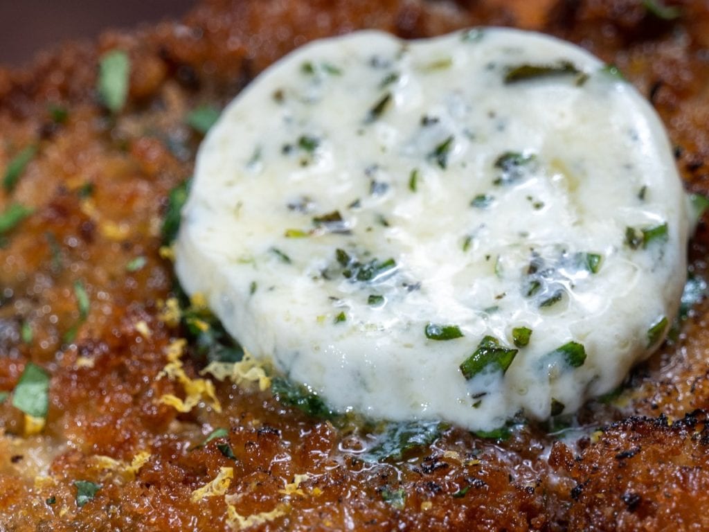 Compound herb butter melting on a piece of Alton Brown's Schnitzel Kiev.