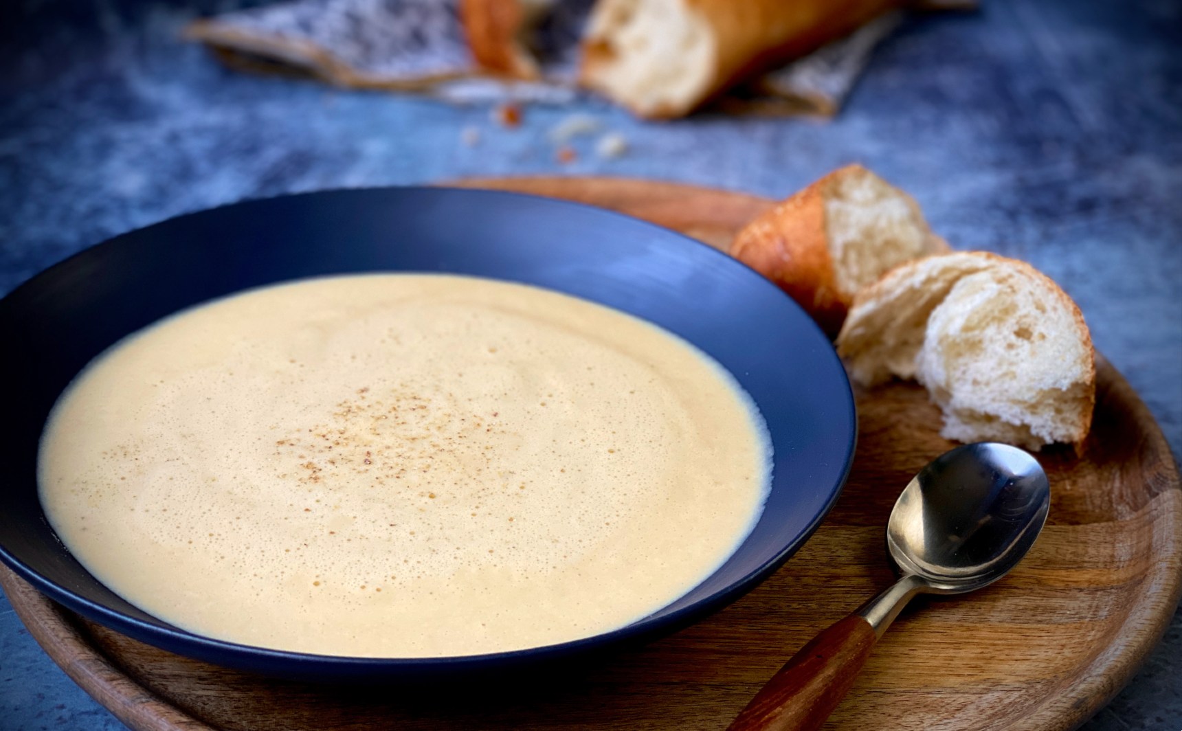 One of the best winter soups: A bowl of cheese soup with torn pieces of baguette and a spoon.